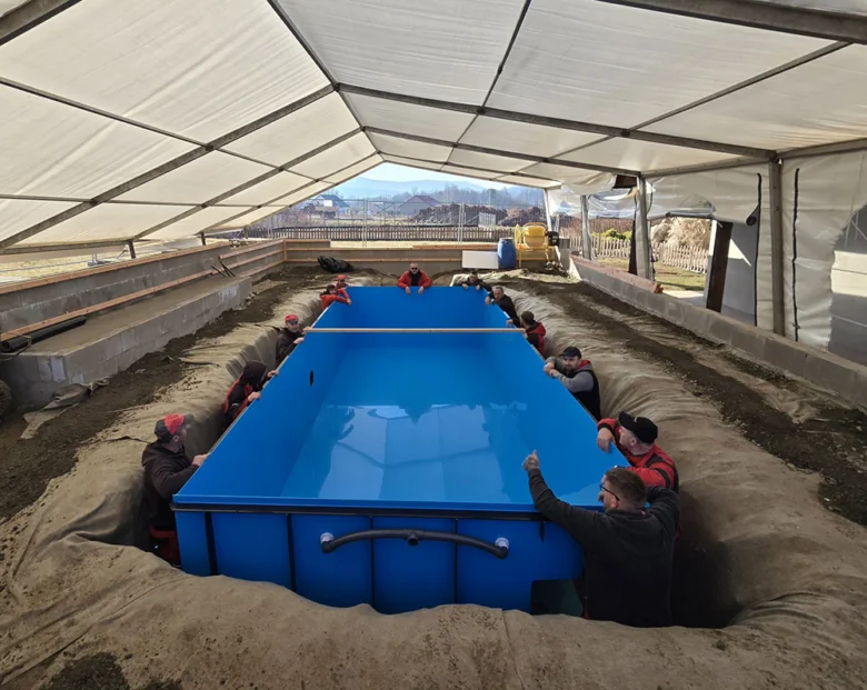 Práce na instalaci podzemního bazénu v zemi s týmem montérů.