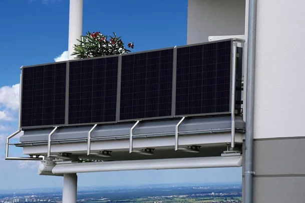 Fotografie fotovoltaických panelů na balkóně s kvetoucí rostlinou.