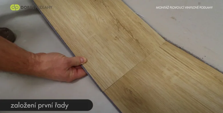 Ruční pokládka vinylové podlahy na vrstvu izolačního materiálu.