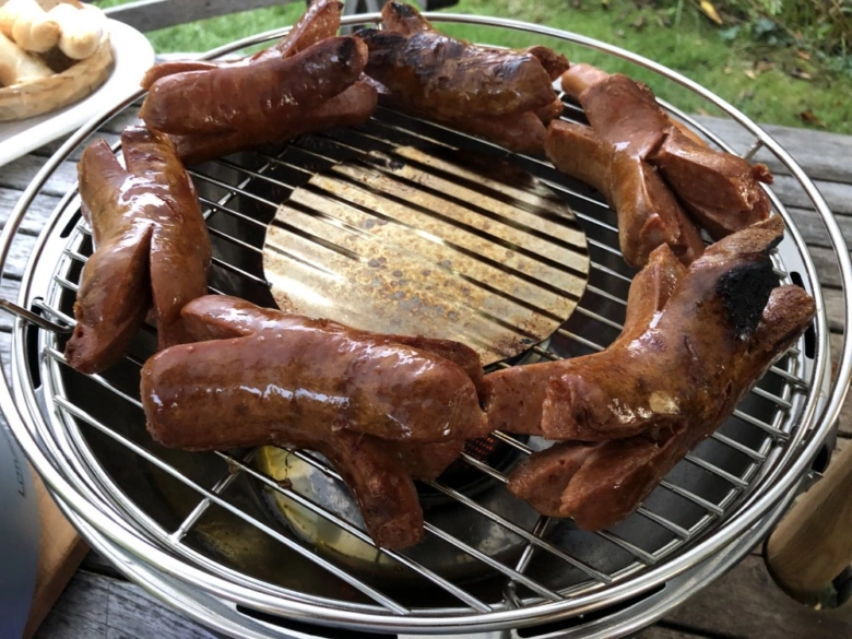 Pečené klobásy na grilu venku, vhodné pro balkon.