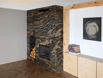 Moderní krb s obklady z černého mramoru v dřevěném rámu.