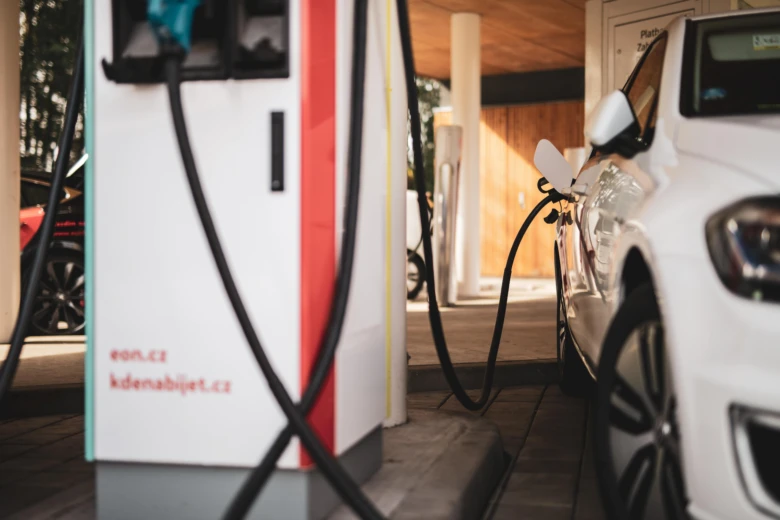 Bílé elektromobil nabíjený na veřejné stanici pro EV.
