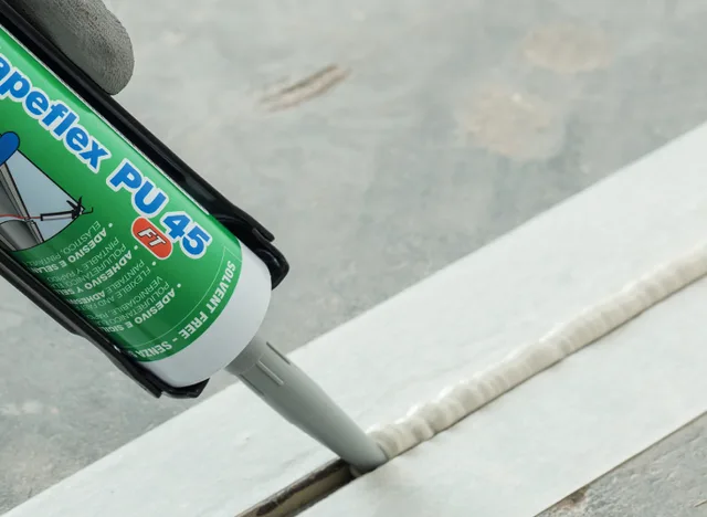 Náplň silikonového tmelu se aplikuje podél hrany v koupelně.