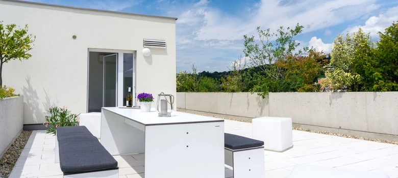 Moderní terasa s velkými skleněnými balkónovými dveřmi vedoucí do interiéru.