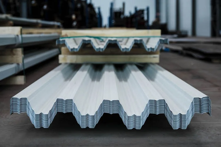 Skládka trapézových plechů na střechu v průmyslovém prostoru.