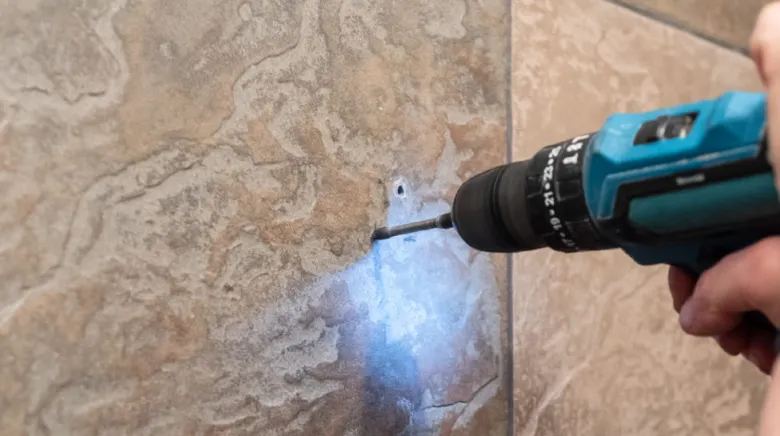 Vrtání do dlaždice pomocí elektrického vrtáku s osvětlením.