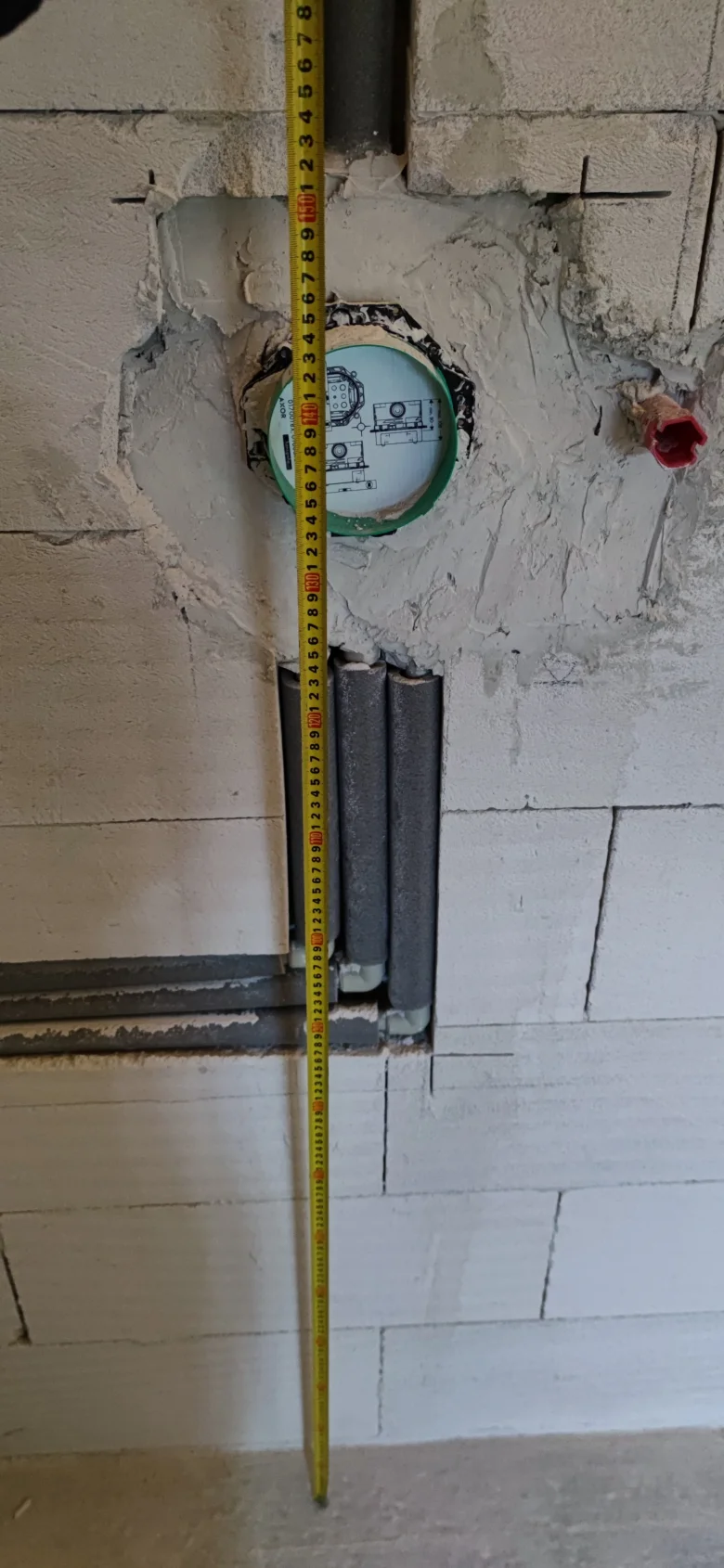 Měření výšky pro instalaci plastových vodovodních trubek v zdi.