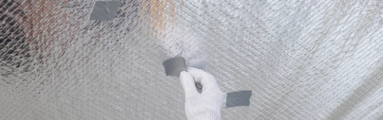 Ruka s rukavicí přitiskuje pásku na střešní fólii.