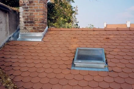 Střecha s lucernou a komínem ukazuje klempířské práce na střeše.