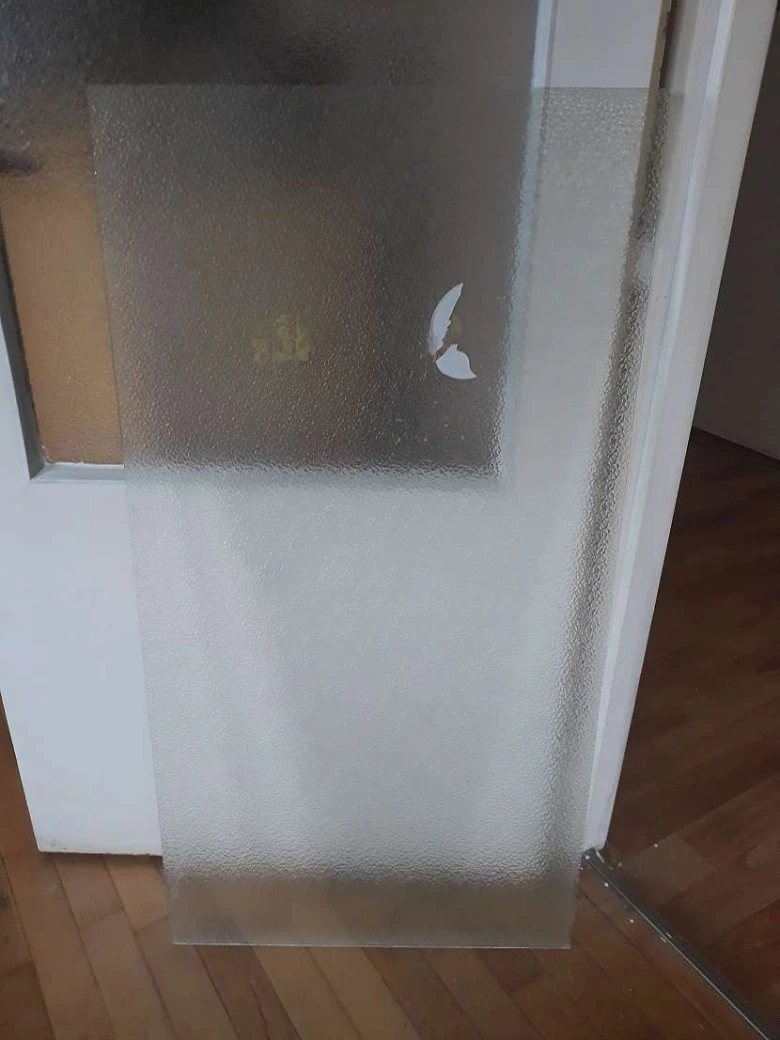 Matná skleněná výplň do bílých dveří na dřevěné podlahě.
