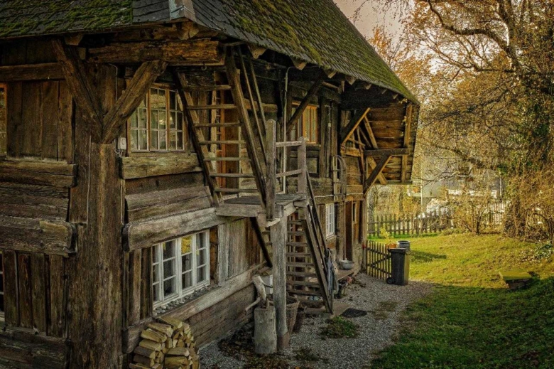 Stará dřevěná stavba s viditelnou konstrukcí v přírodě.