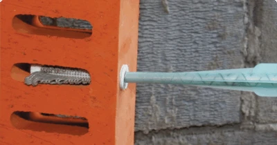 Modrá římsa zasunutá do otvoru v oranžovém cihlovém bloku.