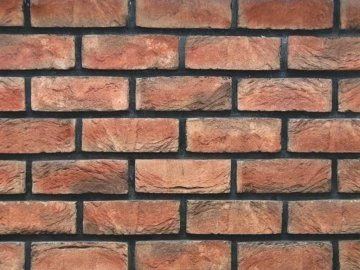 Detail červené klinkerové zdi s tmavými spárami.