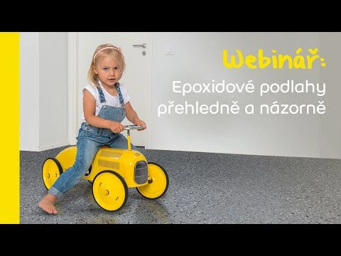 Dítě sedí na žlutém traktoru v místnosti s epoxovou podlahou.