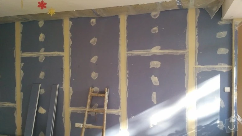 Instalace sádrokartonu na dřevěné trámy v průběhu stavebních prací.