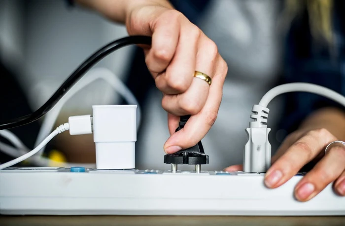 Ruka zapojuje elektrickou zástrčku do zásuvky na rozvodnici.