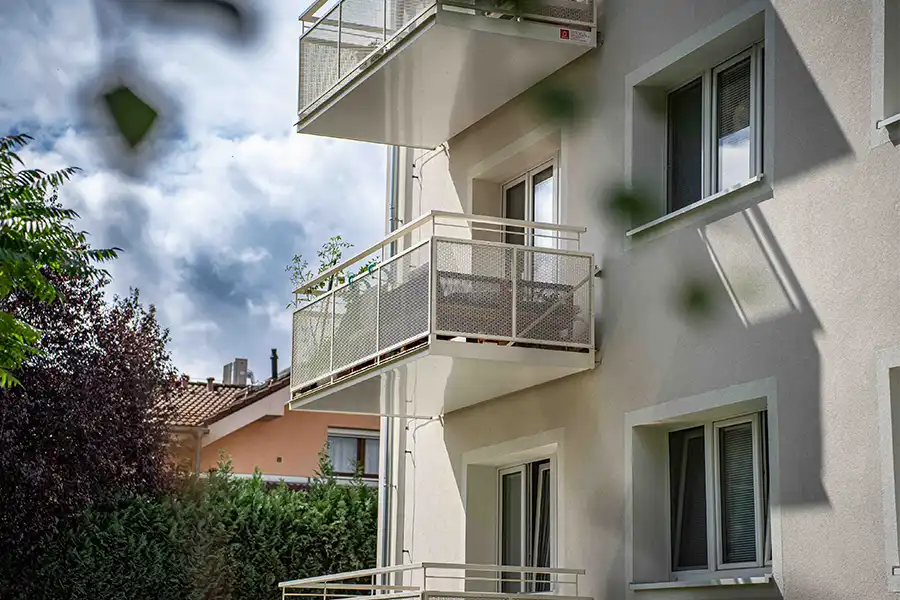 Moderní balkony s kovovými zábradlím a květináči na fasádě bytového domu.