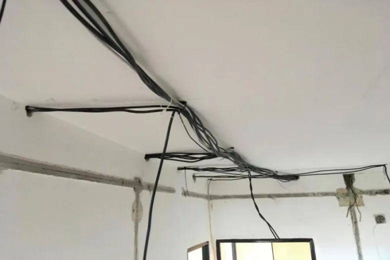 Zamotané elektrické kabely na stropě v bytě během rekonstrukce.