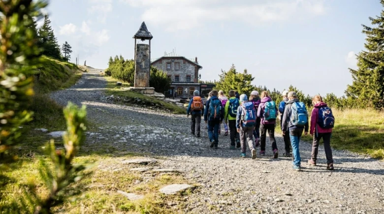 Skupina turistů kráčí po cestě k chatě na Šeráku.
