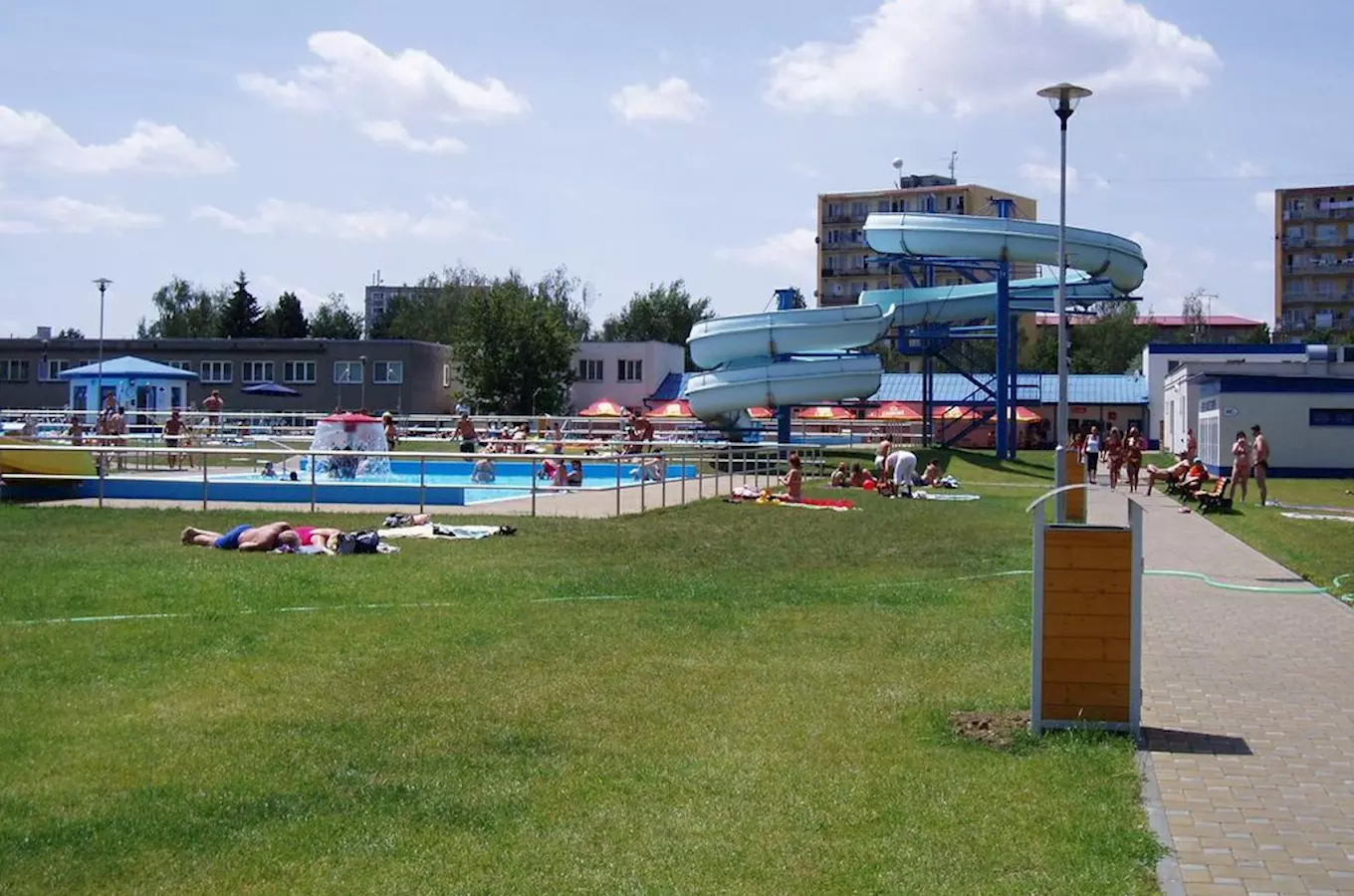 Venkovní bazén s vodními skluzavkami v koupališti pro veřejnost.