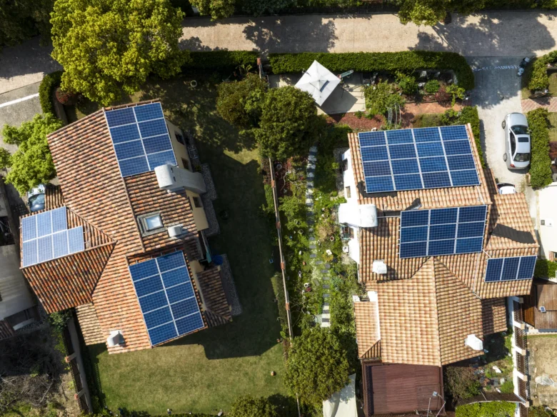 Dvě rodinné domy s fotovoltaickými panely na střechách.
