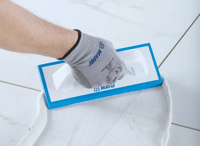 Ručník s rukavicí nanáší hydroizolační směs na dlažbu.