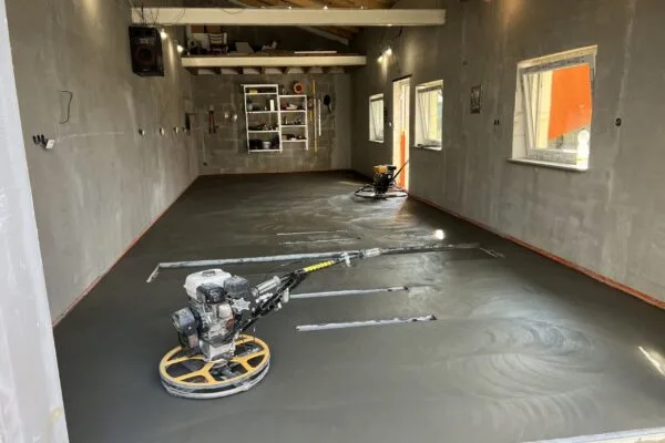 Stroj na leštění nového betonu v prostoru s mokrou podlahou.