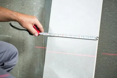 Měření velkoformátového obkladu páskou s červenou laserovou linkou.