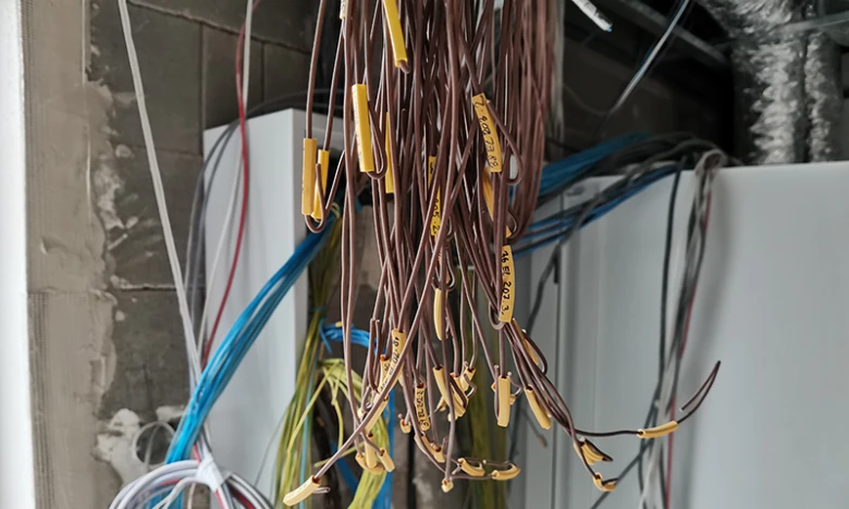 Svisle visící označené elektrické kabely při instalaci v domě.