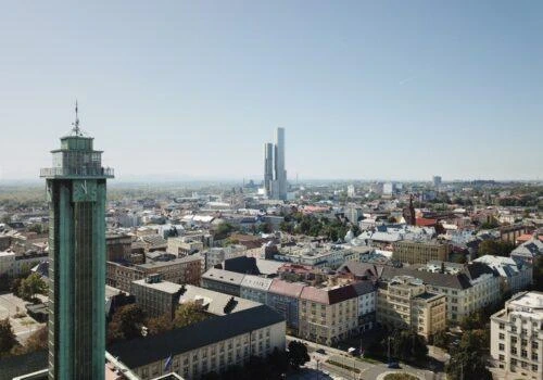 Pohled na ostravské město s věží a mrakodrapy v pozadí.