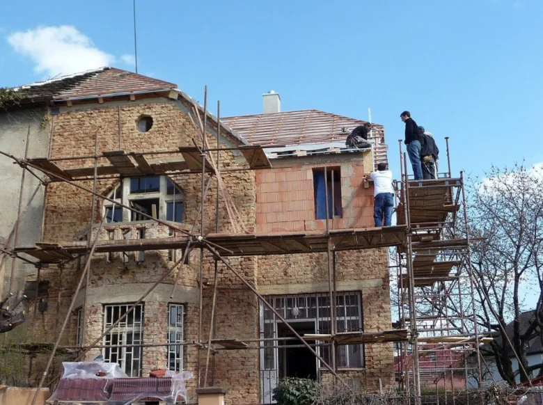 Práce na rekonstrukci domu s dřevěným schodištěm pro stavebníky.