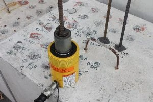 Žlutý hydraulický lis pro montáž chemické kotvy do betonu.