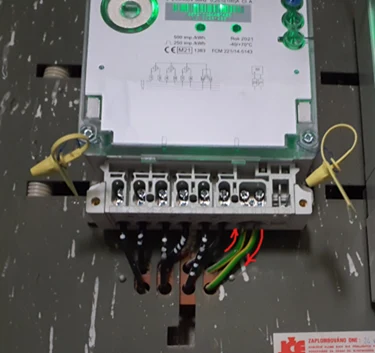 Elektrický měřič energie s připojenými vodiči na rozvaděči.