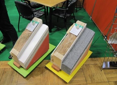 Modely dřevostavebních stěn s izolačními vrstvami na výstavním pultu.