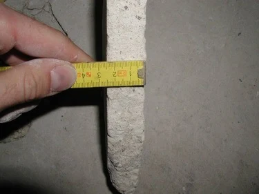 Měření tloušťky betonového potěru páskou.