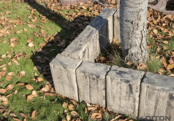 Nainstalované betonové obrubníky kolem stromu na trávníku.