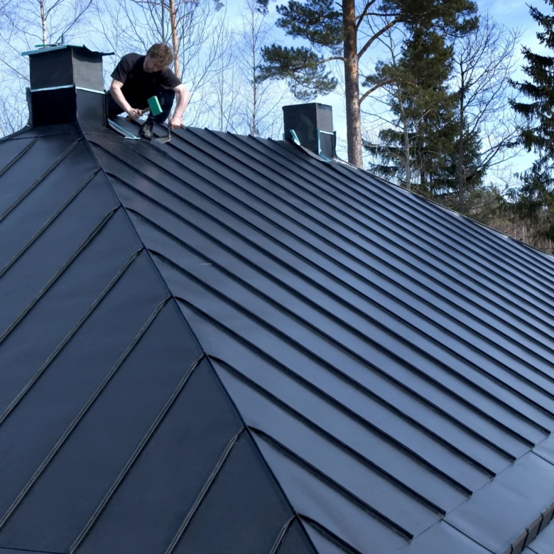Instalace tmavých plechových střech kolem komína.