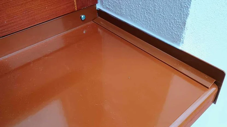 Hnědý vnitřní parapet u zdi s texturou.