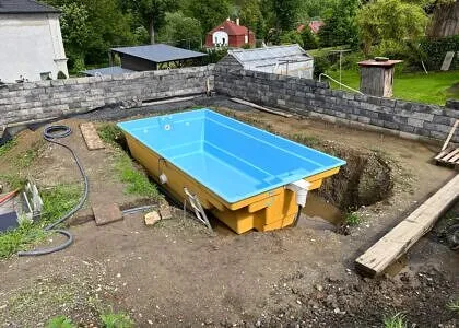 Zapuštěný bazén v procesu instalace s vykopaným jámou.