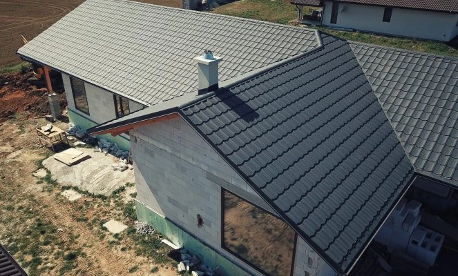Vazníková střecha s šedými taškami na domě ve výstavbě.