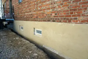 Venkovní vápenná omítka na zdivu s okny v přízemí.