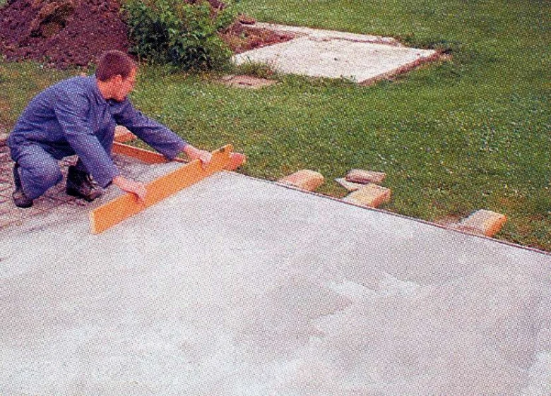 Muž hladí čerstvý beton pro venkovní kuchyň