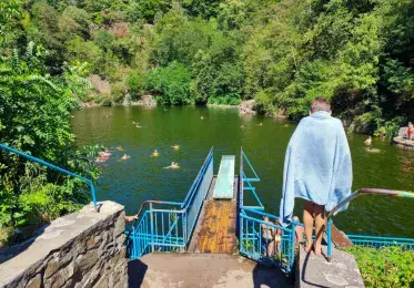Koupaliště v bývalém lomu s bazénem uprostřed zelené přírody.
