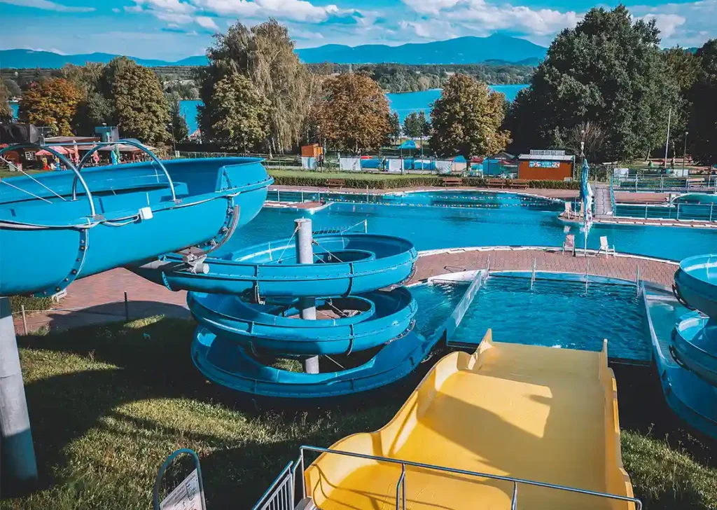 Modré vodní skluzavky v bazénu akvaparku Olešná s horami na pozadí.