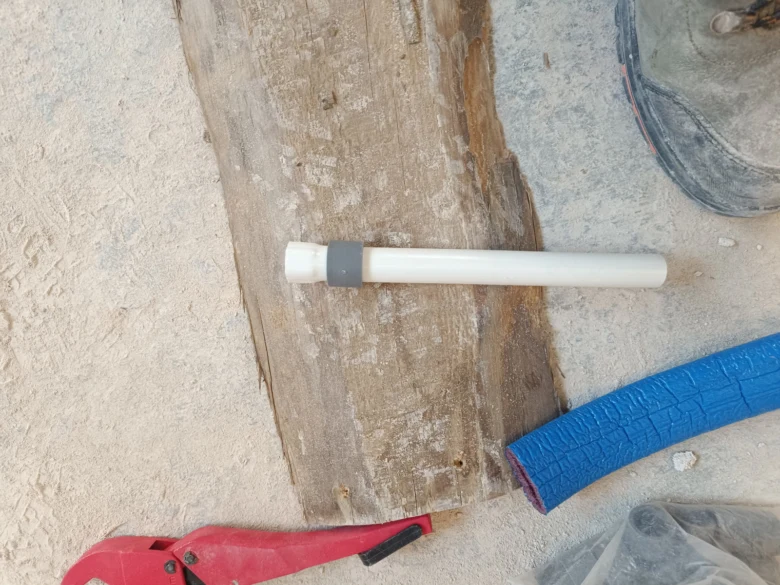 Bílá plastová trubka s nástroji pro domácí instalaci vody.