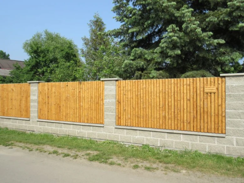 Dřevěný plot na betonovém základu venku.