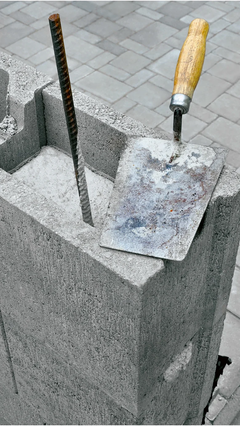 Ukázka betonu s výztuží a nástroji pro stavbu zdí.
