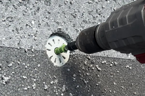 Vrták s kotvou v děře ve styroporu na fasádě.