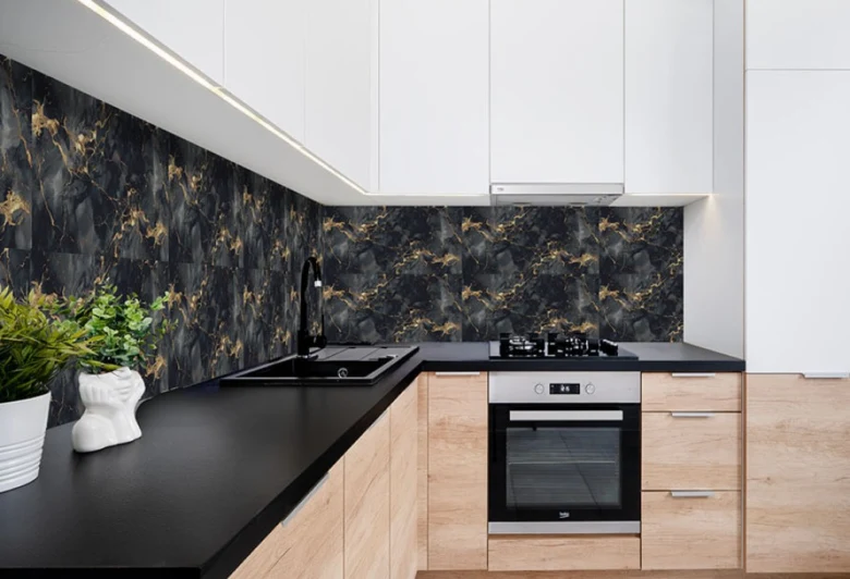 Moderní kuchyň s černou pracovní deskou a mramorovým obkladem.