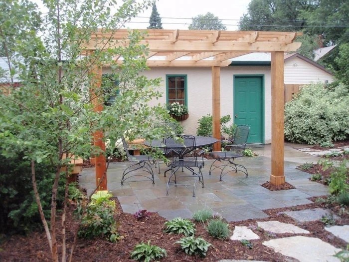 Dokončená dřevěná pergola na zahradním terasu s kameny.